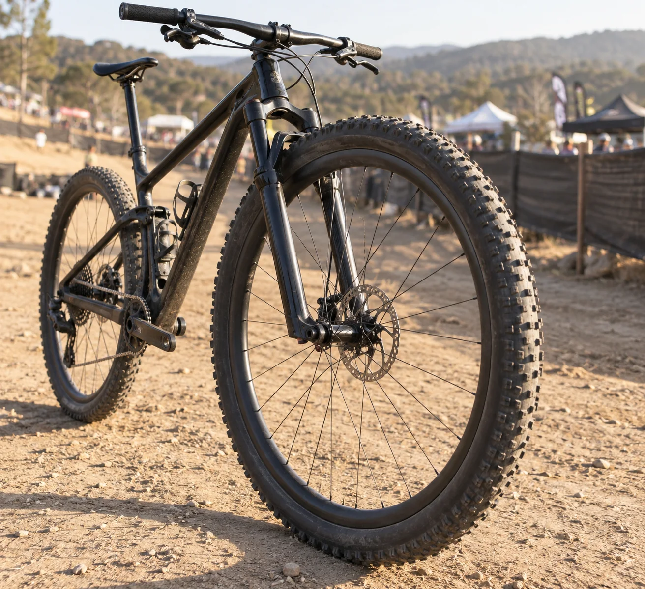 Roue VTT 32 pouces à pneu cranté montée sur un vélo de cross-country posé dans la poussière d'un site de course